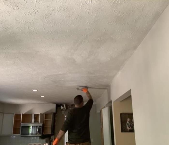employee cleaning ceiling after fire